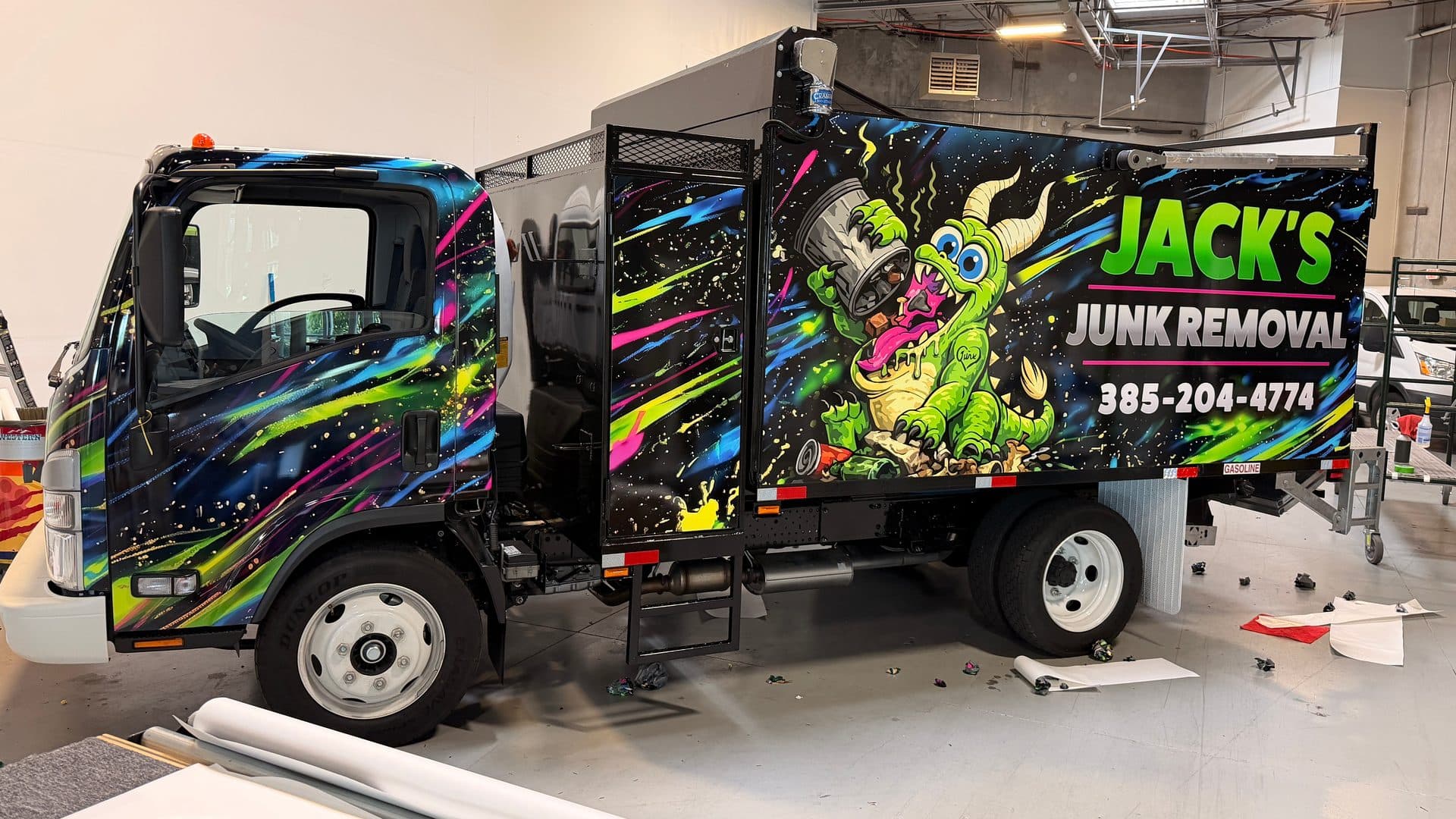 The Jack's Junk Removal wrap installed on a real Isuzu NPR truck inside the Identity Graphx install bay